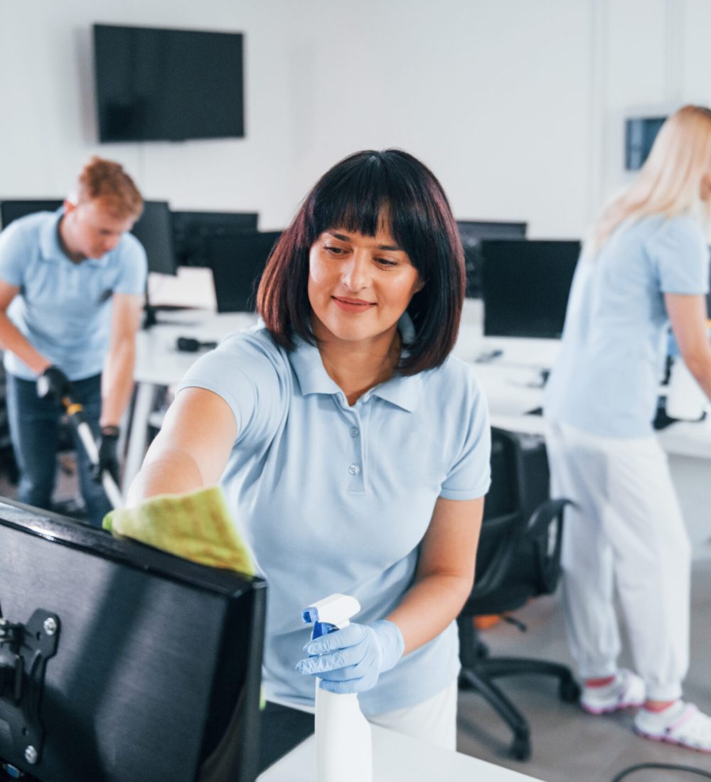 Group of workers clean modern office together at daytime.